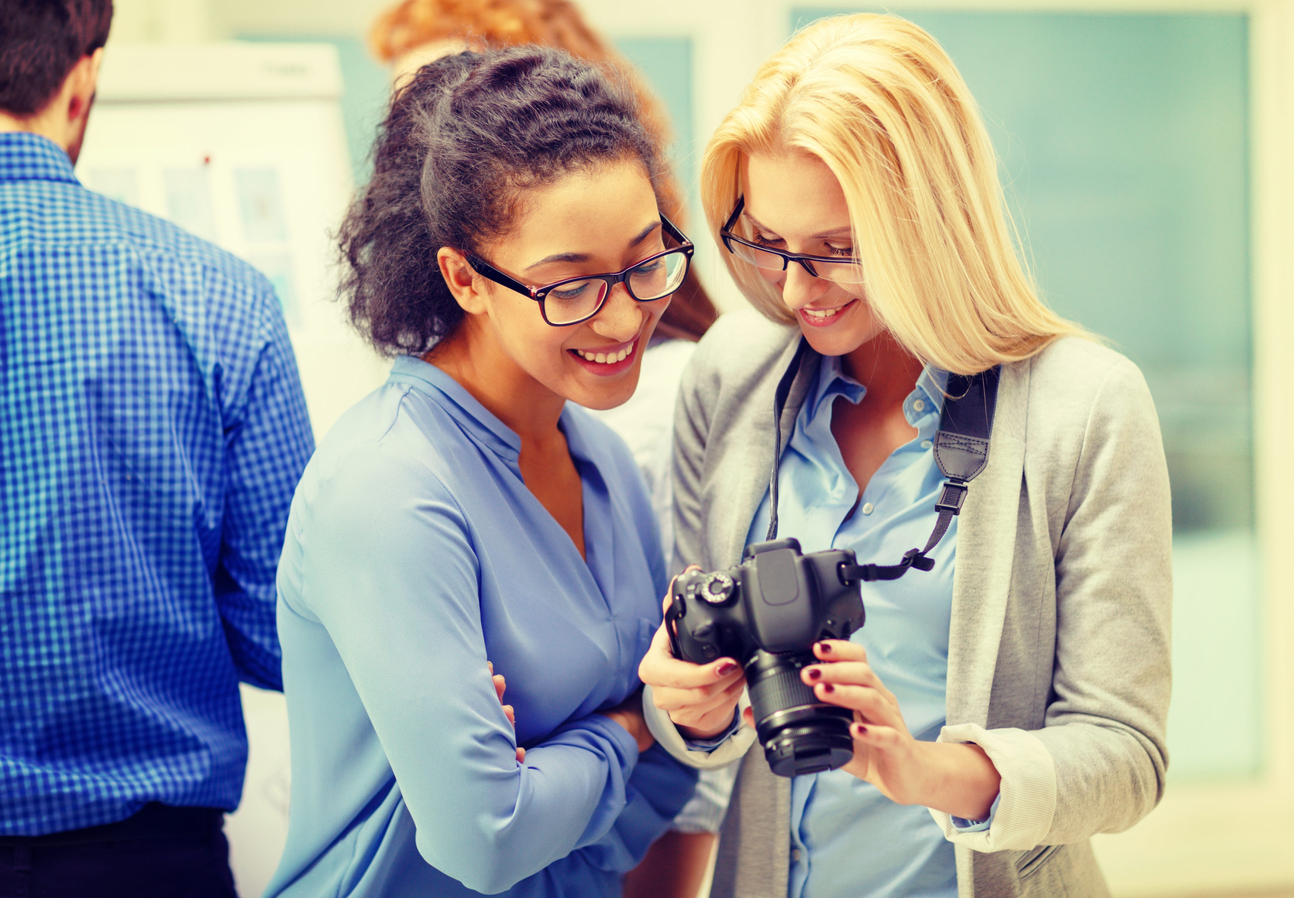 Photo illustrant l'article : Débat : afficher ou ne pas afficher sa photo quand on est professionnel de santé ? On y voit au premier plan deux personne entrain de discuter dont l'une avec un appareil à photo.